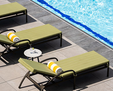 Lounge chairs uniformly positioned poolside at a Life Time outdoor pool