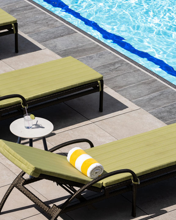 Lounge chairs uniformly positioned poolside at a Life Time outdoor pool