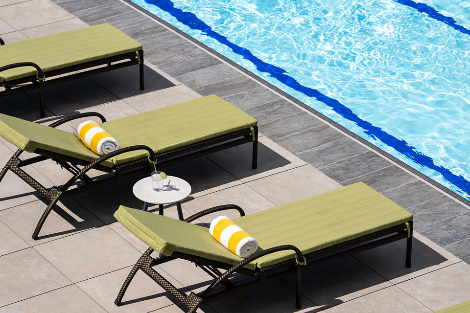 Lounge chairs uniformly positioned poolside at a Life Time outdoor pool