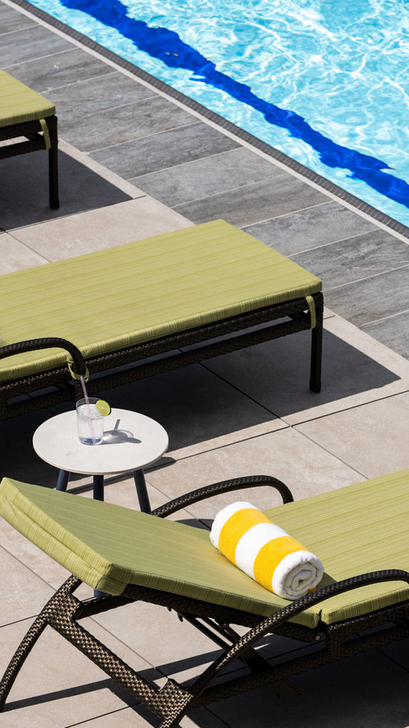 Lounge chairs uniformly positioned poolside at a Life Time outdoor pool