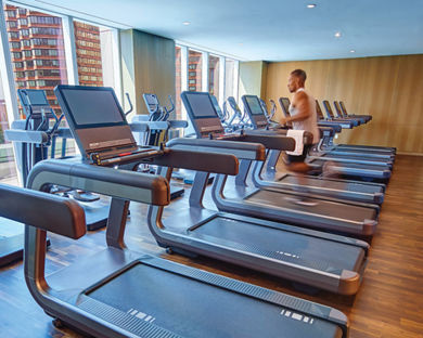 A man running on a treadmill looking through windows onto an urban setting