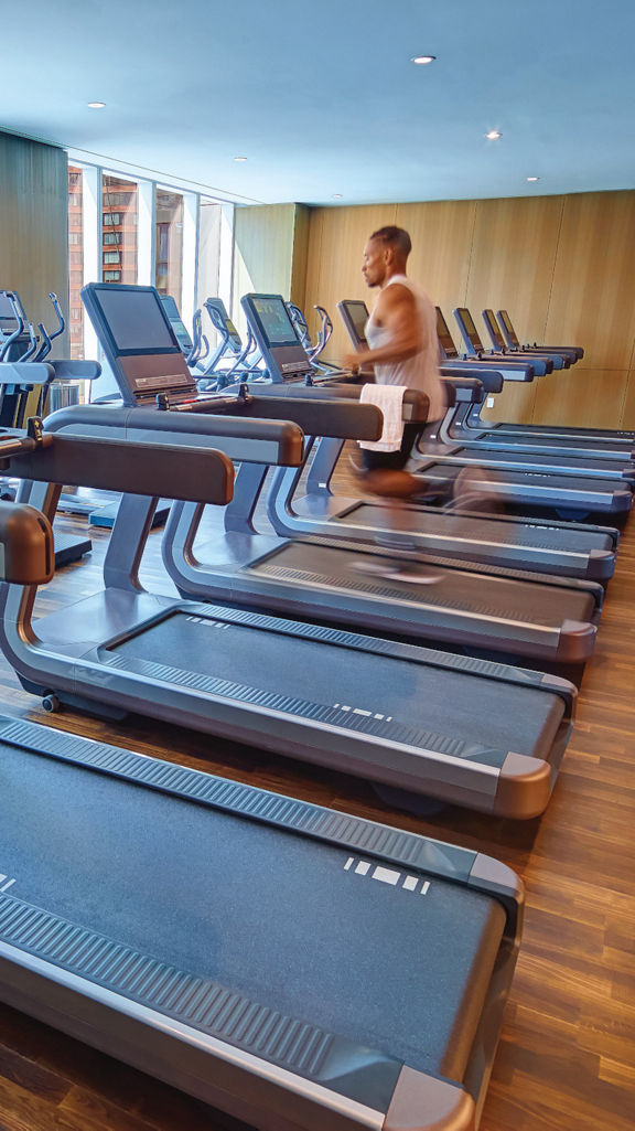 A man running on a treadmill looking through windows onto an urban setting