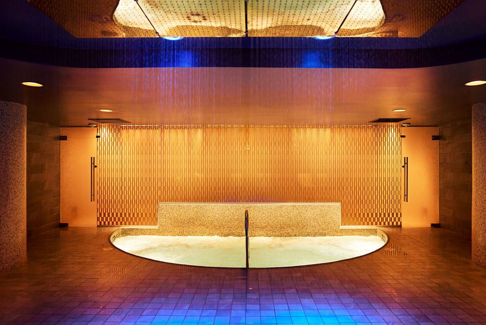 An indoor whirlpool lit with amber tones located in the Life Time Sky club located in New York