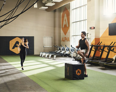 A male doing box jumps and a female jogging in an Alpha Studio