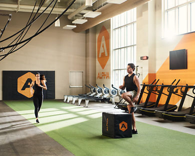 A male doing box jumps and a female jogging in an Alpha Studio