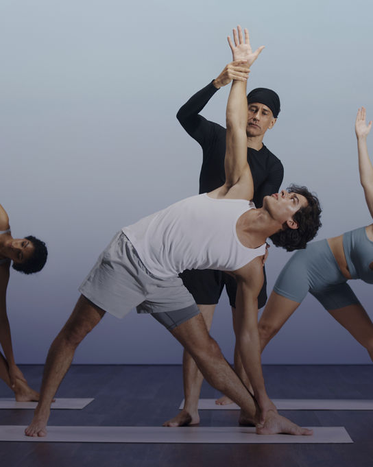 Sol yoga instructor guiding a participant into triangle pose at Life Time