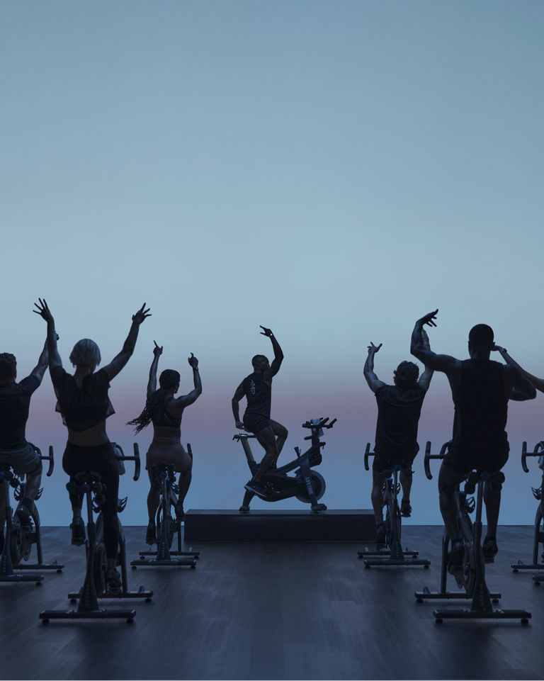 AMP spin class riding together with their hands up