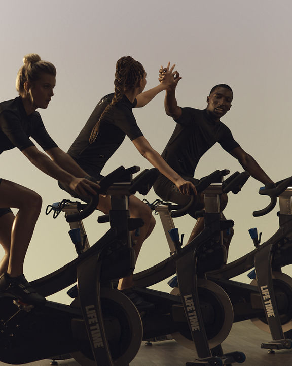 Cyclists in a PWR spin class at Life Time high fiving