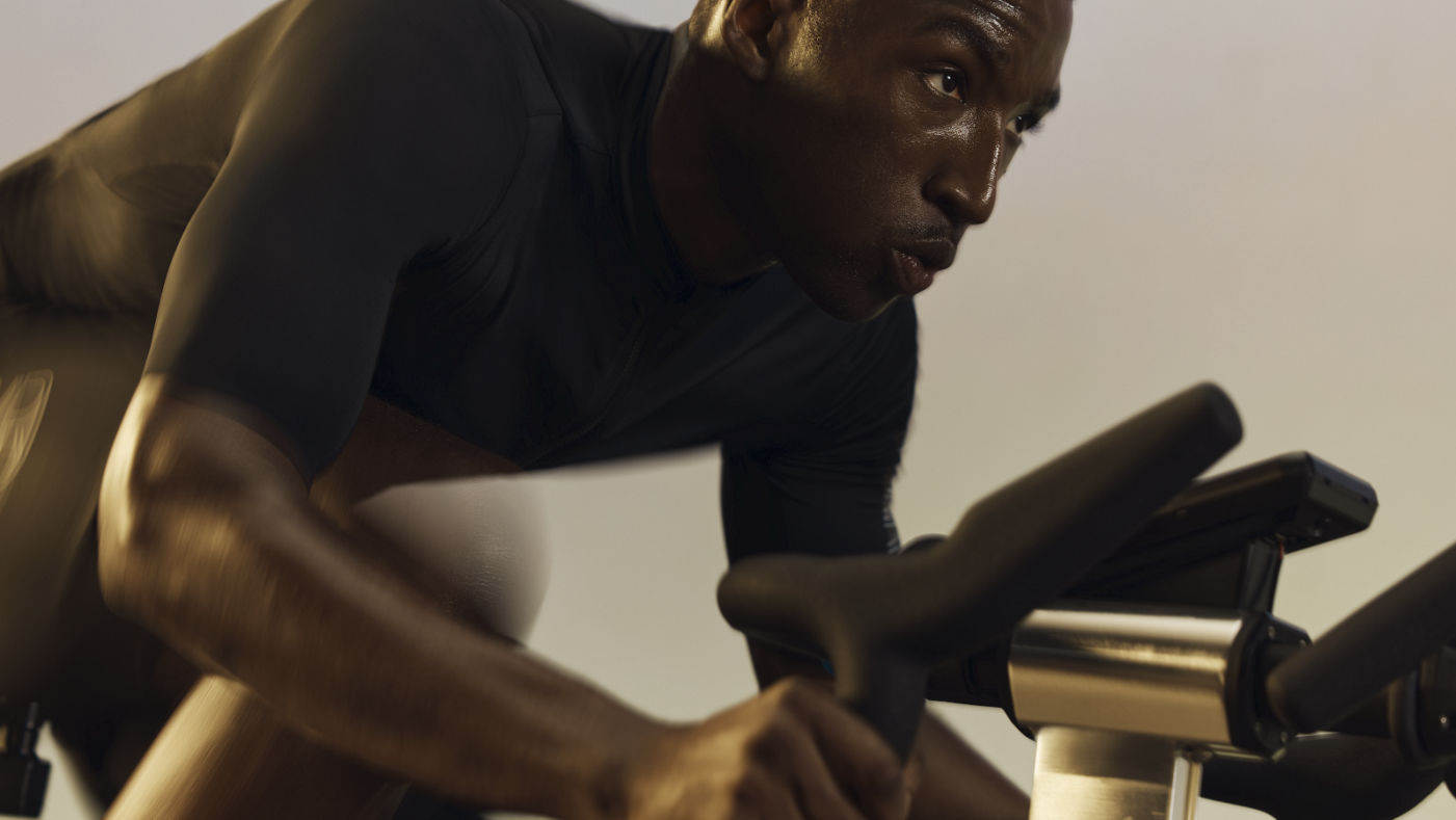 A cyclist seated and sprinting during a PWR spin class