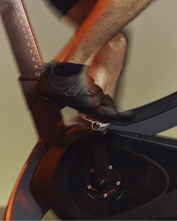 Close up of the pedals and a cyclist clipped into the bike during a PWR spin class