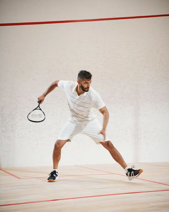 a man gets ready to take a swing while playing squash