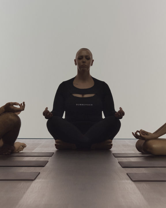 Instructor leading a group meditation at a surrender yoga class