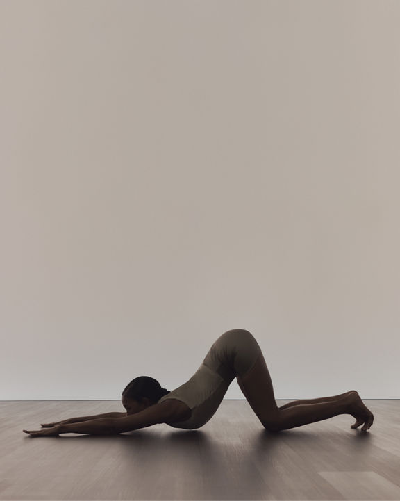 Profile of a person in puppy pose during a surrender yoga class