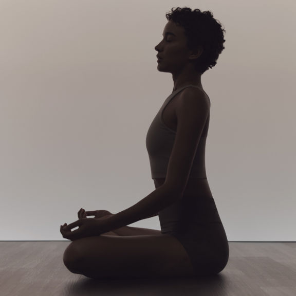 Woman in calm seated sukhasana pose during a surrender yoga class