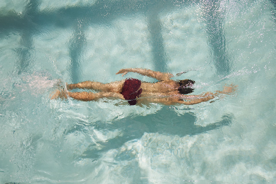 A man swims underwater in an outdoor pool