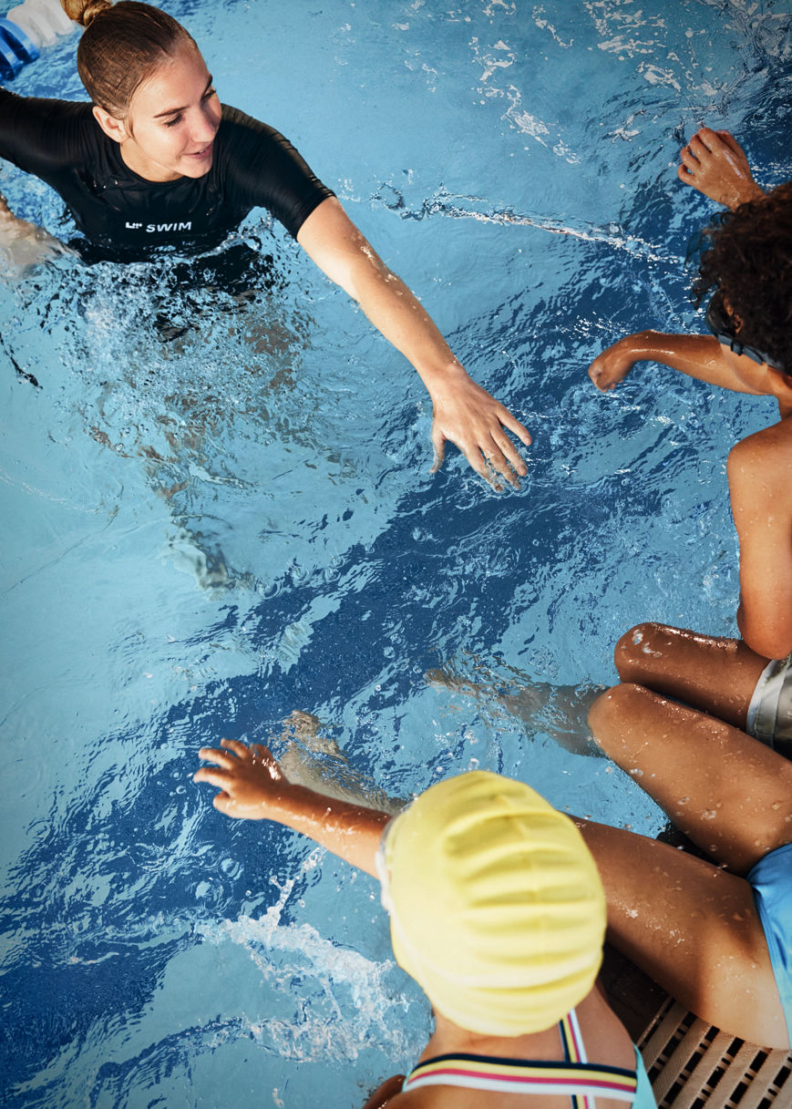 an instrutor standing in the water holding her arm out