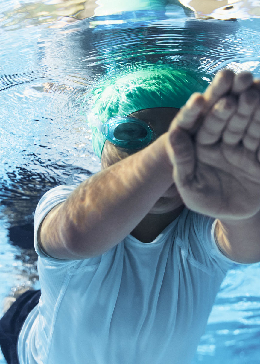 a boy in a green swim cap swimming under water
