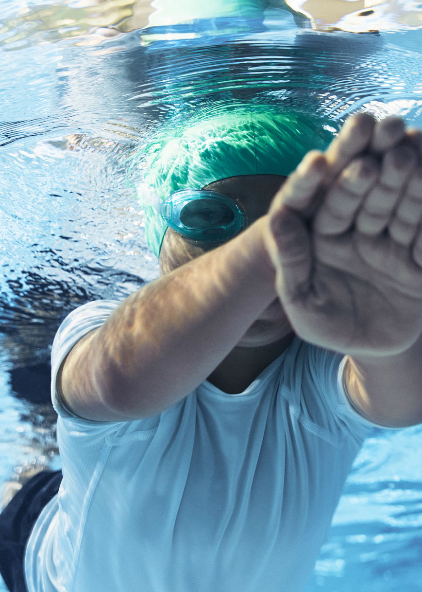 a boy in a green swim cap swimming under water