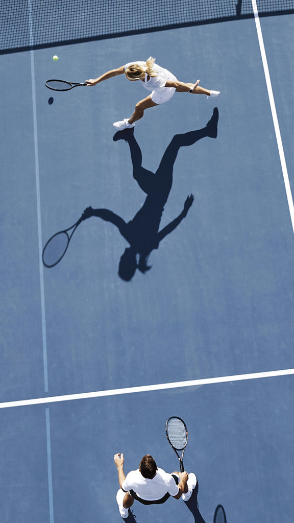 Aerial view of two people playing tennis on an outdoor tennis court