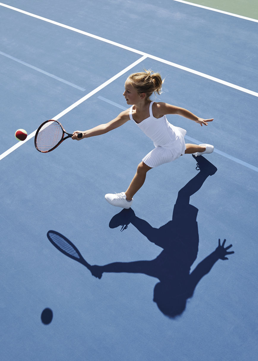 Aerial view of a young girl playing tennis on an outdoor tennis court