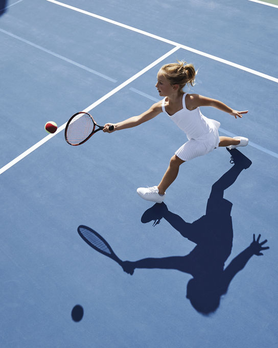 Aerial view of a young girl playing tennis on an outdoor tennis court