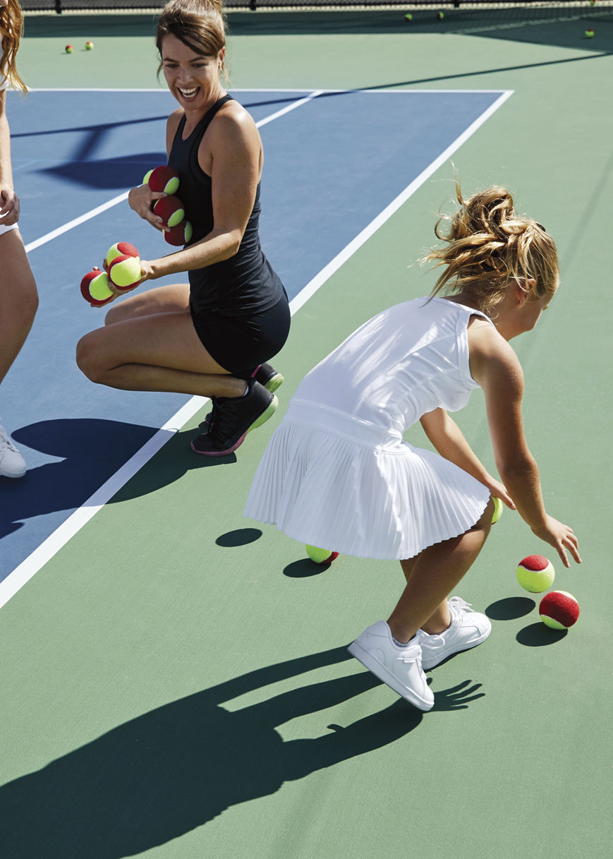 A group of children playing tennis on an outdoor tennis court