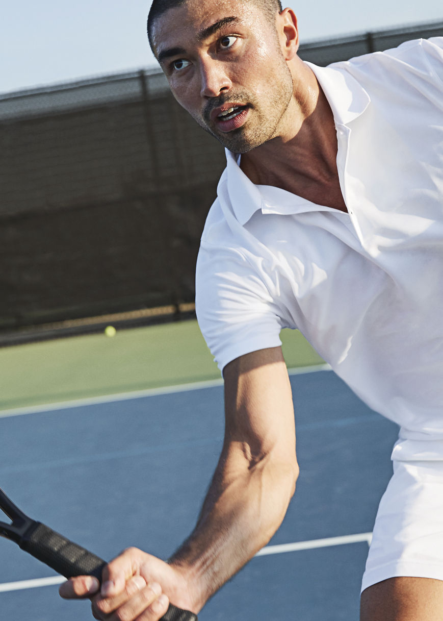 Man playing tennis on an outdoor tennis court at Life Time