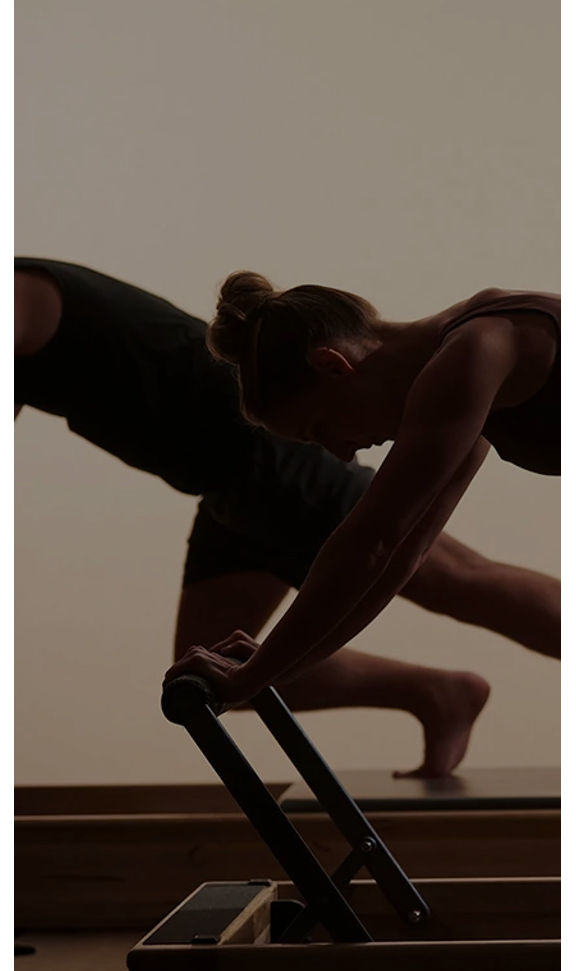 A man and a woman working out on a reformer in a pilates class