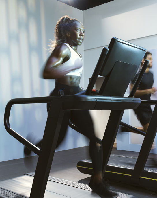 Woman sprinting on a treadmill in the UltraFit boutique group training class