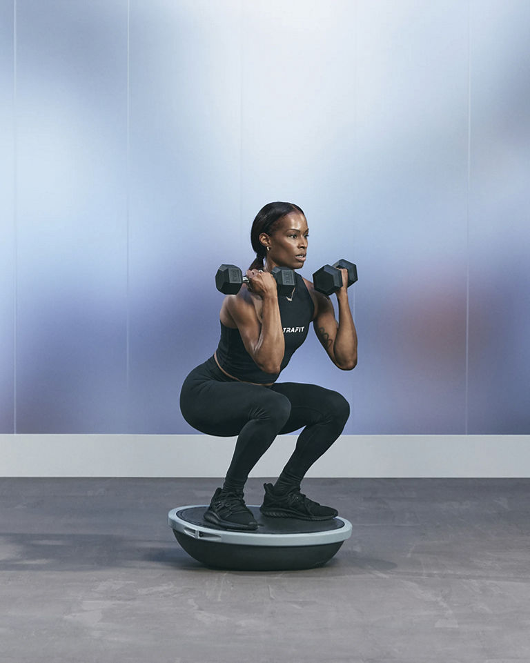 a woman doing an isolated squat curl on a bosu