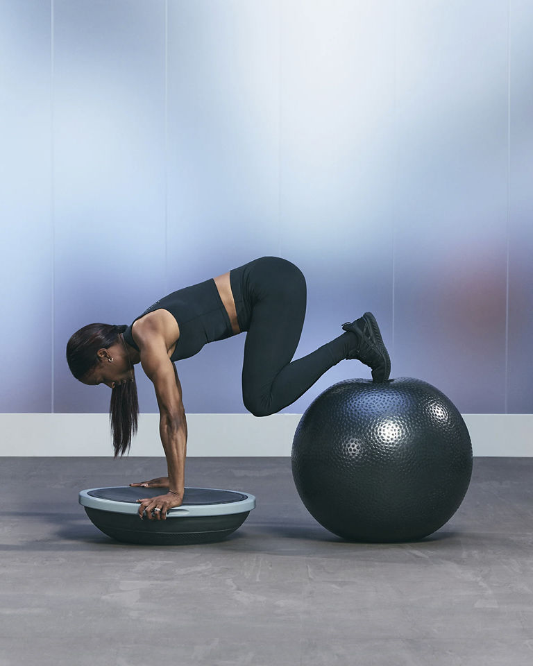 a woman doing a knee plank on a bosu ball