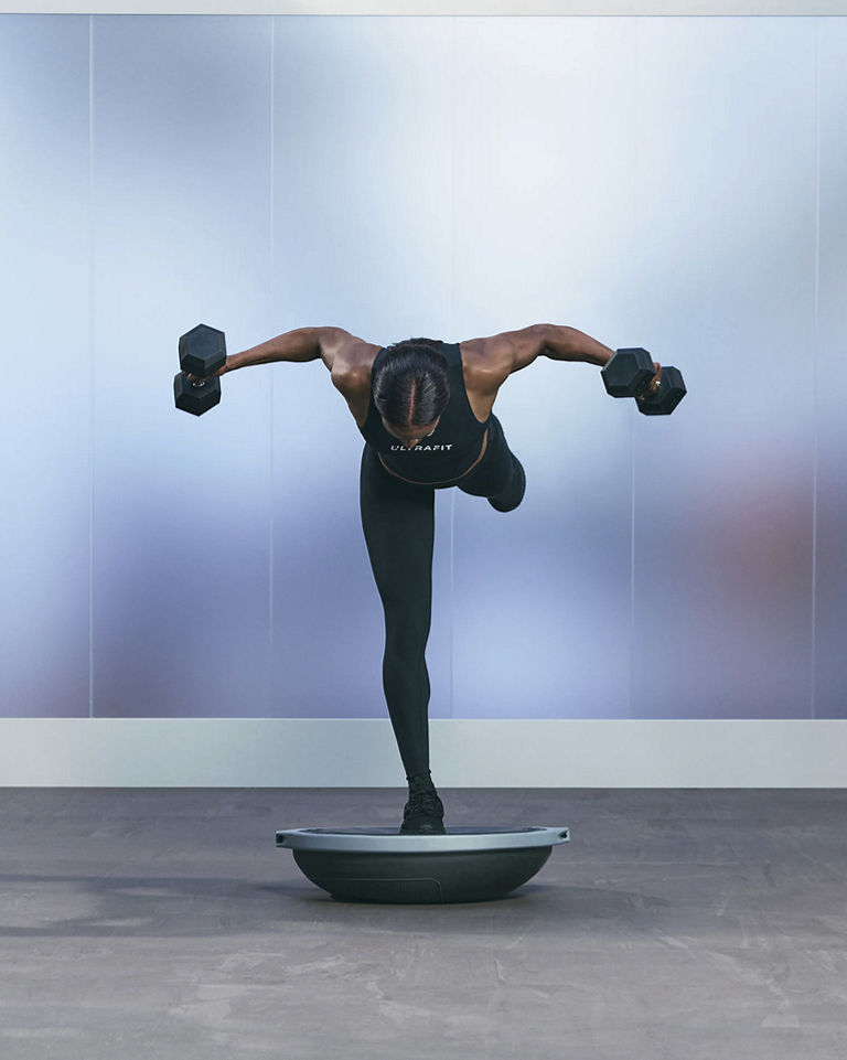 a woman doing a single leg bosu bent over fly pose