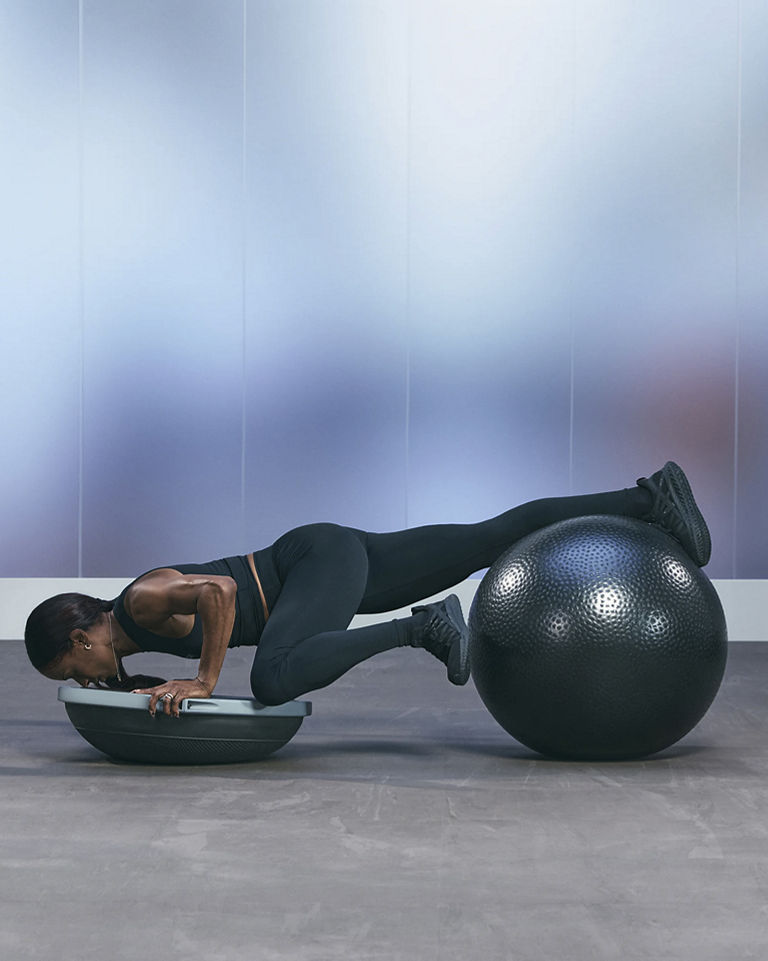 a woman doing a spiderman pushup on a bosu and stability ball