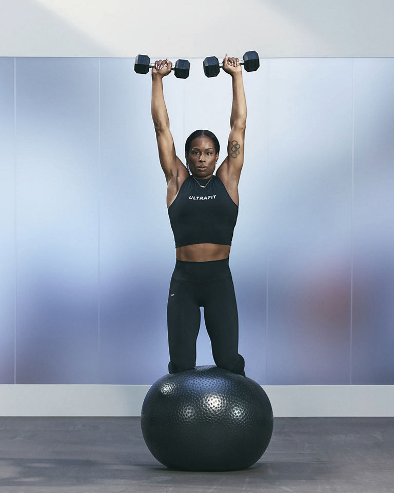 a woman doing a kneeling shoulder press on a stability ball
