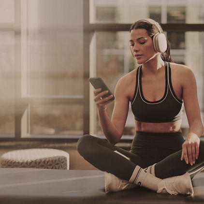 woman sitting on a pilates table looking at a phone