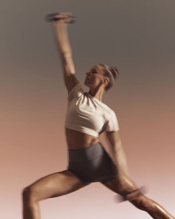 Participant in lunge with arm extended during warrior sculpt yoga class at Life Time