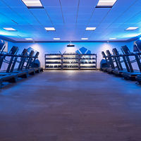 GTX studio filled with treadmills, and hand weights under a blue-toned light