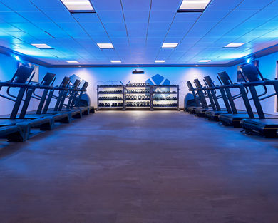 GTX studio filled with treadmills, and hand weights under a blue-toned light