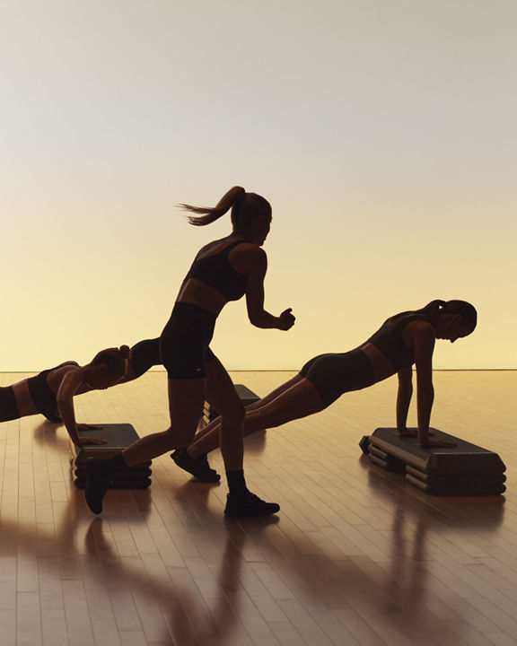 Xtreme cardio class members doing skaters and using step benches at Life Time