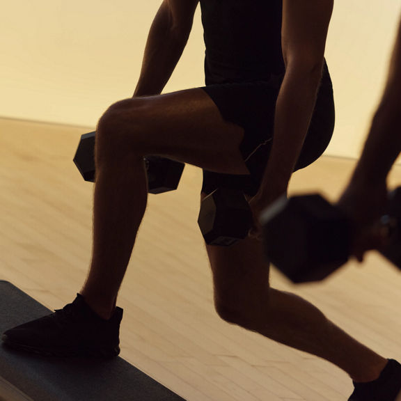 Xtreme cardio class member in split squat at Life Time