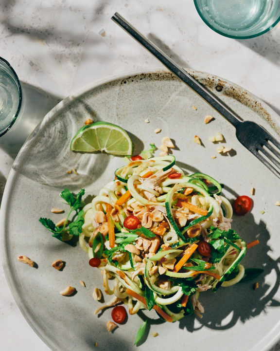 Overhead view of a plate topped with zucchini noodles and a lime slice