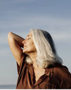 Active mature beautiful woman enjoying the beach in the morning wearing brown dress in front of the sea