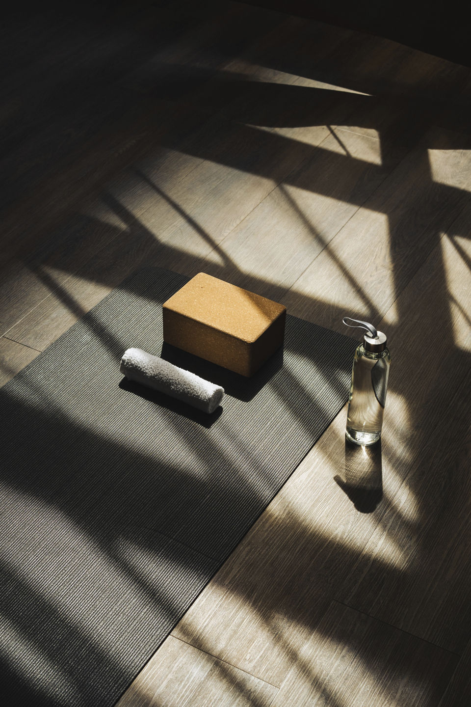 A waterbottle, yoga block, and towel sit by a yoga mat