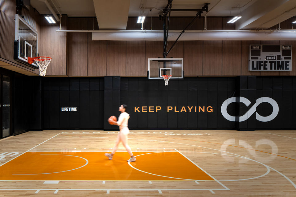 A woman holding a basketball walking towards a basketball hoop