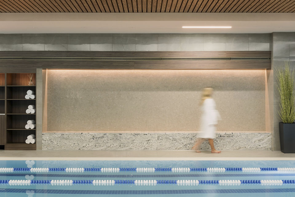 An out-of-focus female walking poolside wearing a white robe