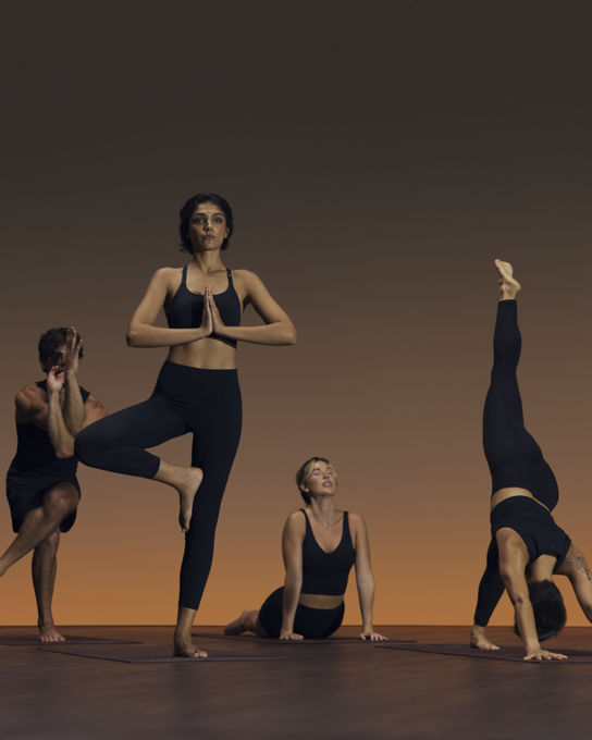 Group of six people in varying yoga poses at a flow yoga class