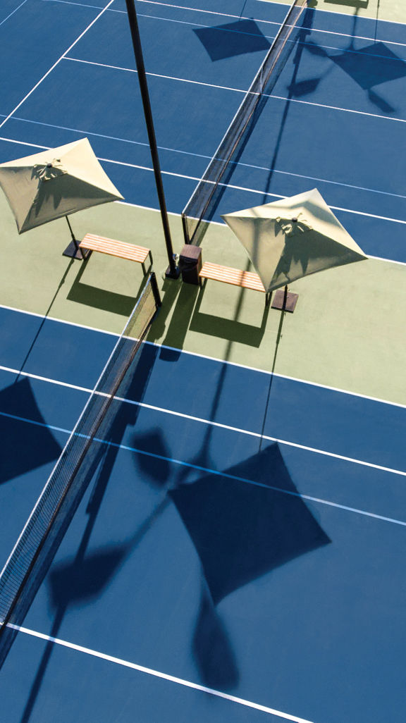Aerial view of outdoor tennis courts with benches and umbrellas at our Folsom, California club location.