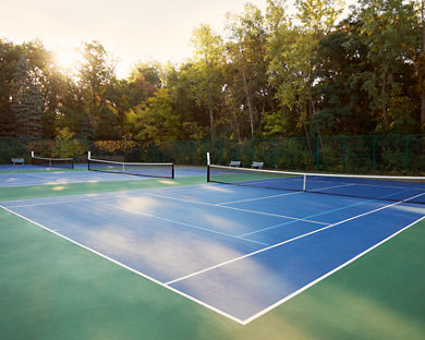 Outdoor tennis courts surrounded by trees at the Fridley Life Time club location