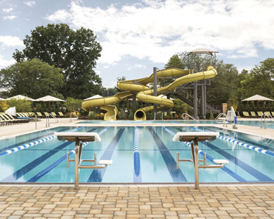 Outdoor lap pool with lane lines and a large waterslide at Life Time
