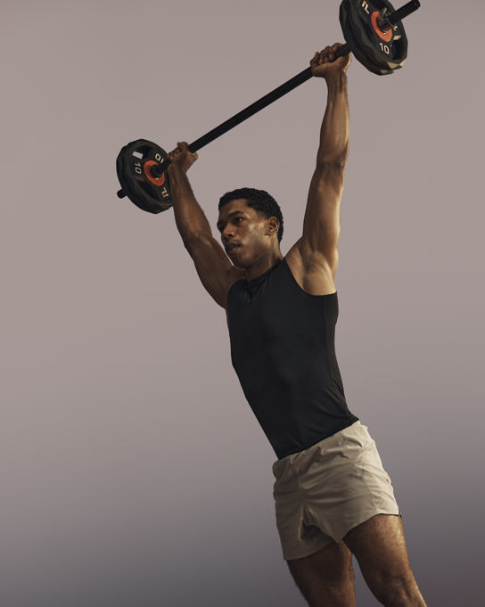 Life Time member lifting a barbell overhead in a strength class